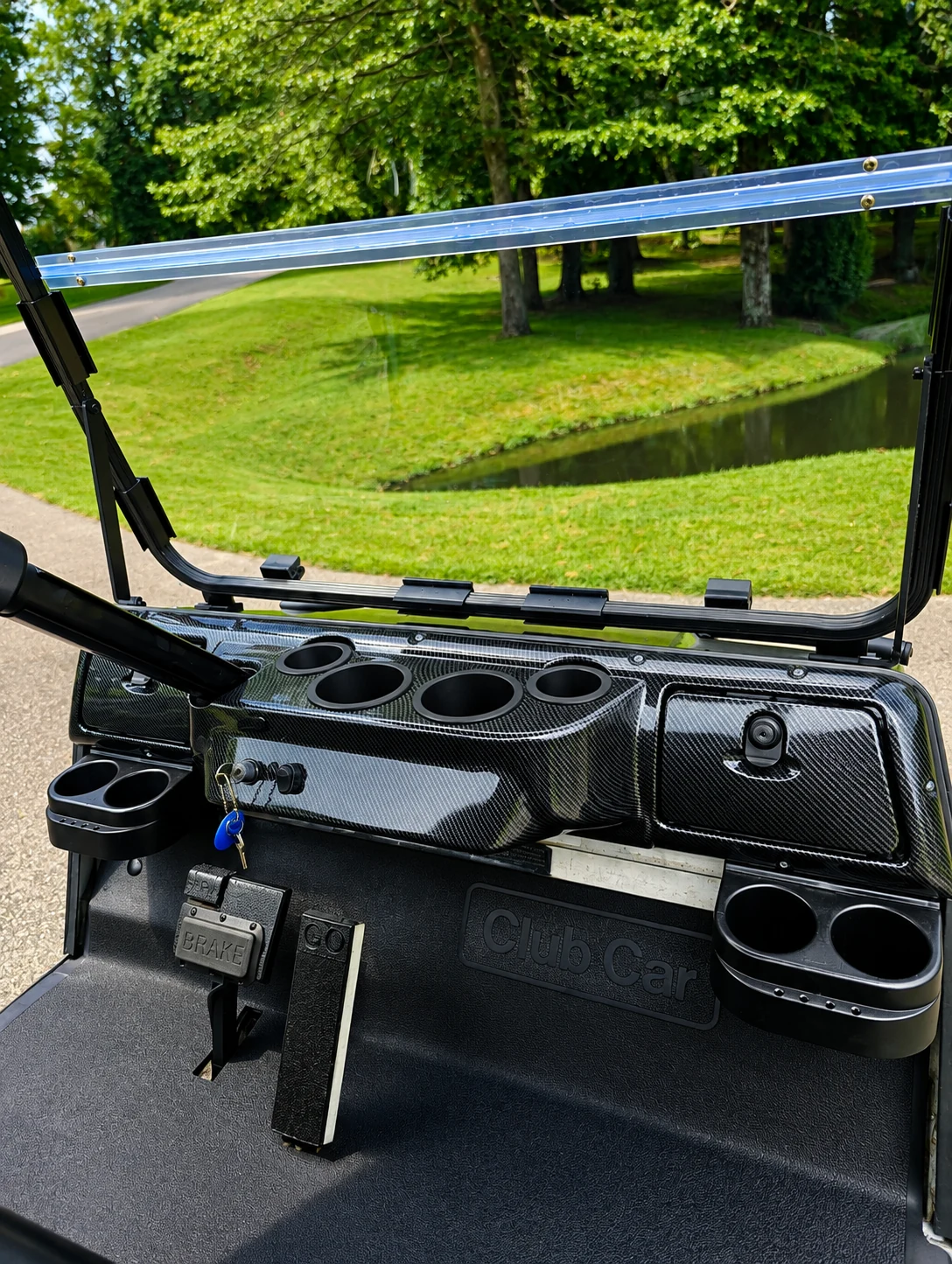 Carbon-fiber-style custom dashboard installed on a Club Car golf cart with storage compartments and cup holders