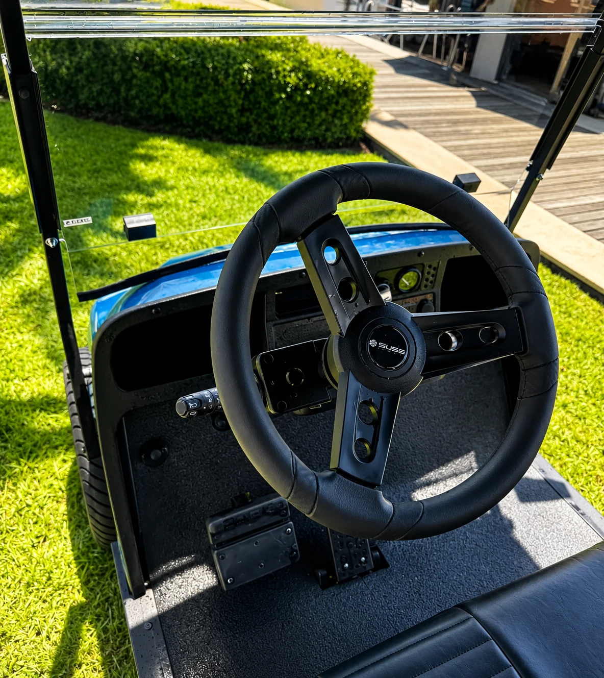 Black custom three-spoke steering wheel installed on a blue golf cart