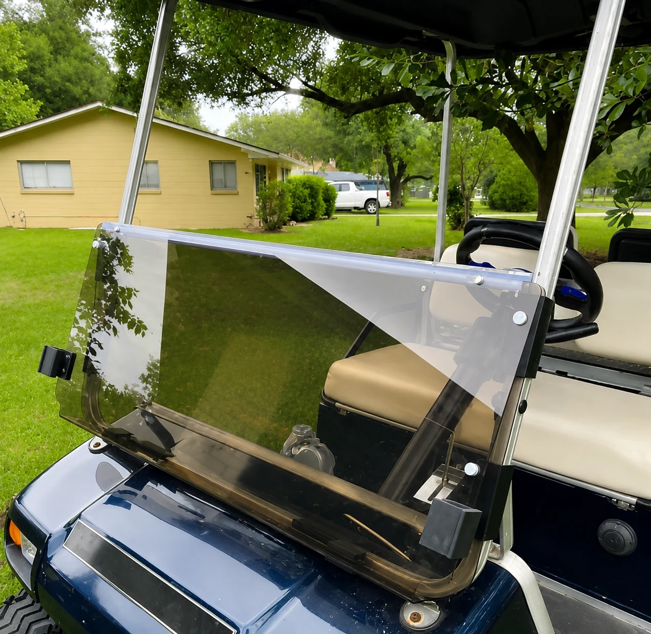 Clear folding windshield installed on a blue golf cart